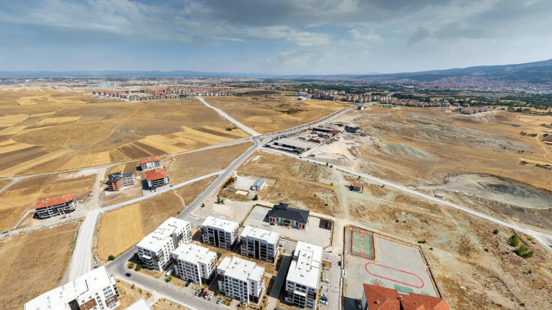 BT Çinikent projesi yatırım arazisinin kuş bakışı drone görüntüsü, çevresindeki mevcut yapılaşma ve ana yollar net bir şekilde görülüyor.