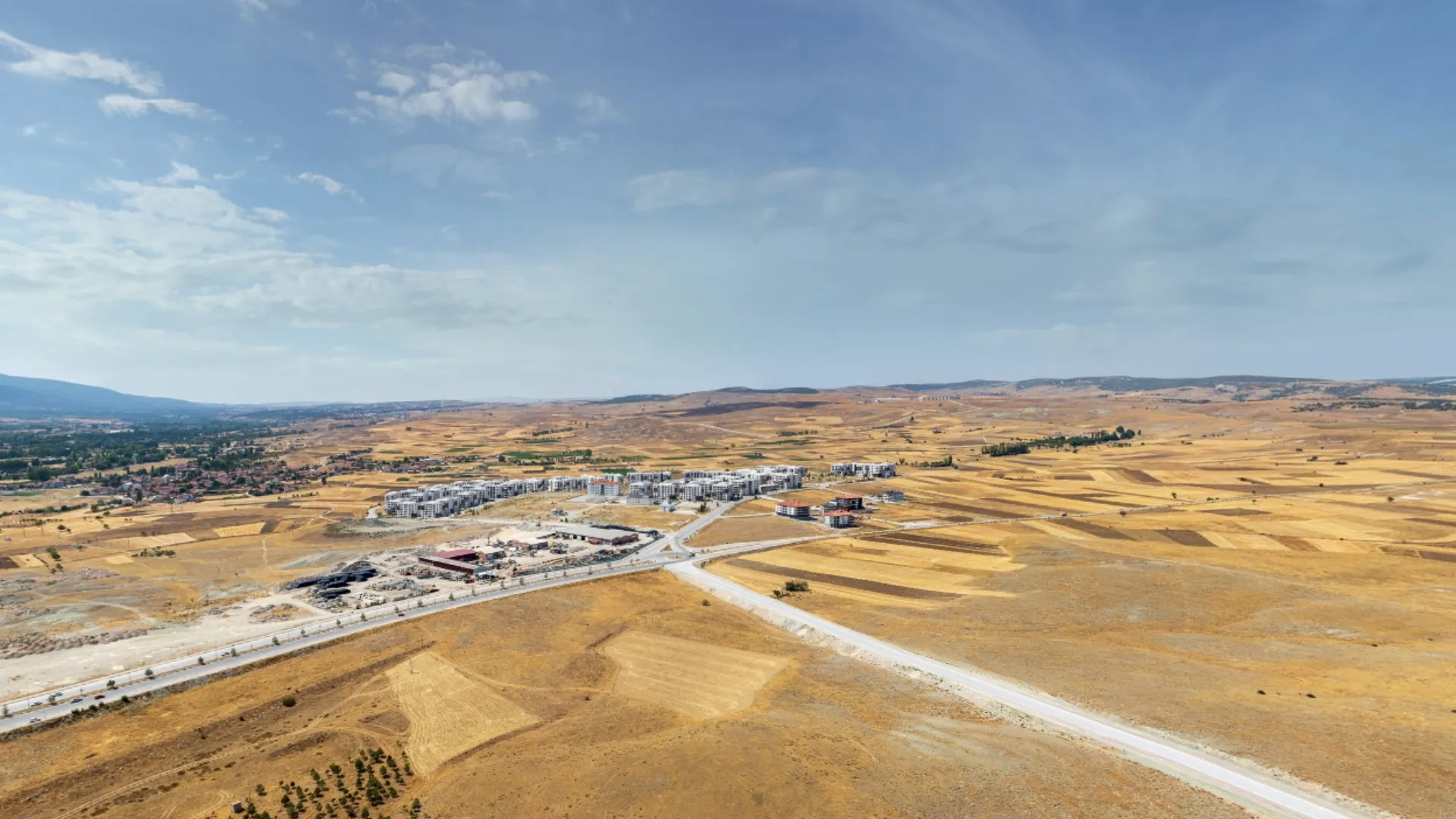 BT Çinikent proje alanının çevresindeki tamamlanmış konut projeleri ve sosyal donatı alanlarını içeren panoramik drone görüntüsü.